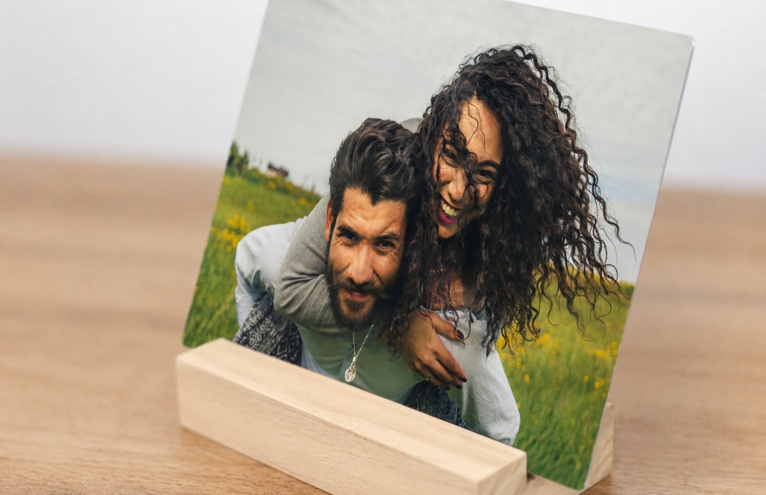 Side view of a desk print of a laughing couple resting in its solid wood display stand