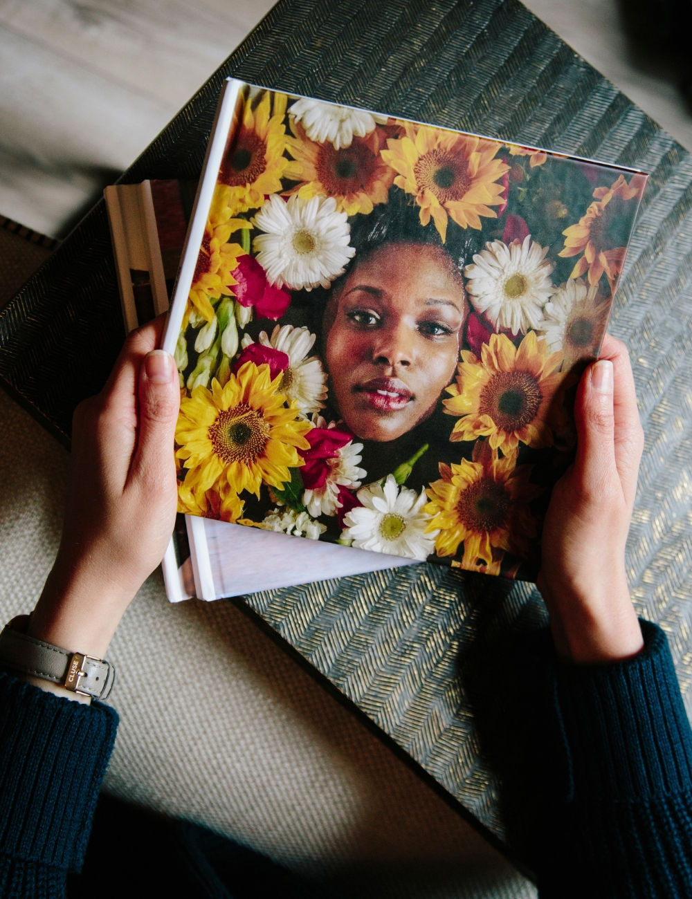 Someone holding a SimplePrints hardcover photo book with a women's face peaking out of flowers.