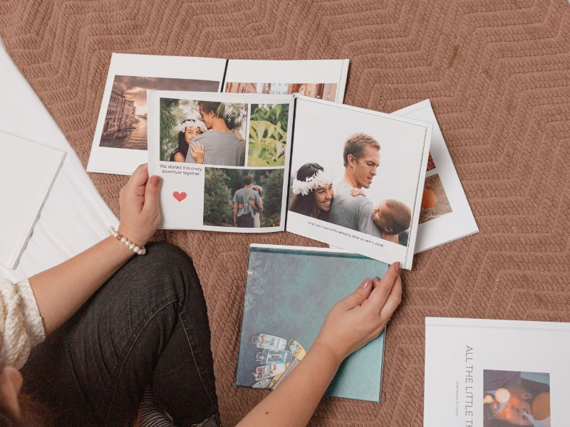 Person holding a SimplePrints photo books and other photo books laid on top of a bed