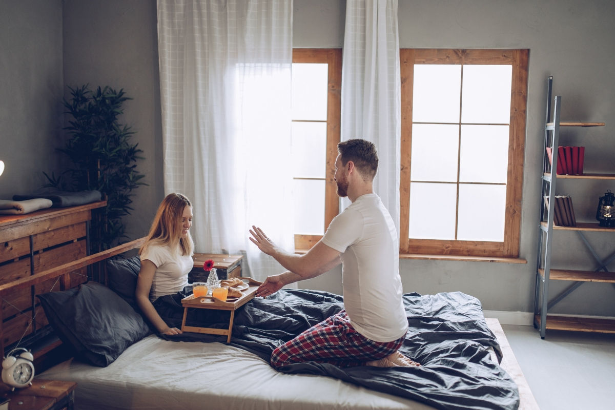 a man offering breakfast to a woman in bed