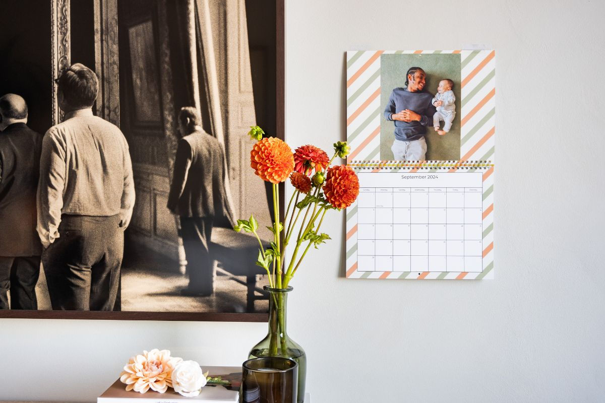 A Calendar pinned to the wall with a photo of a father and his baby sun on a stripe background