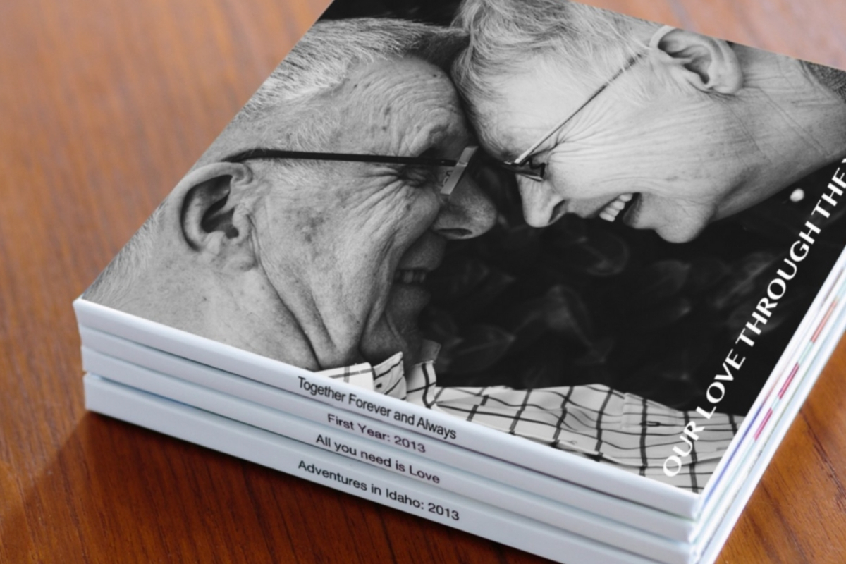 A stack of photo books, the top cover showing an elderly couple smiling at each other