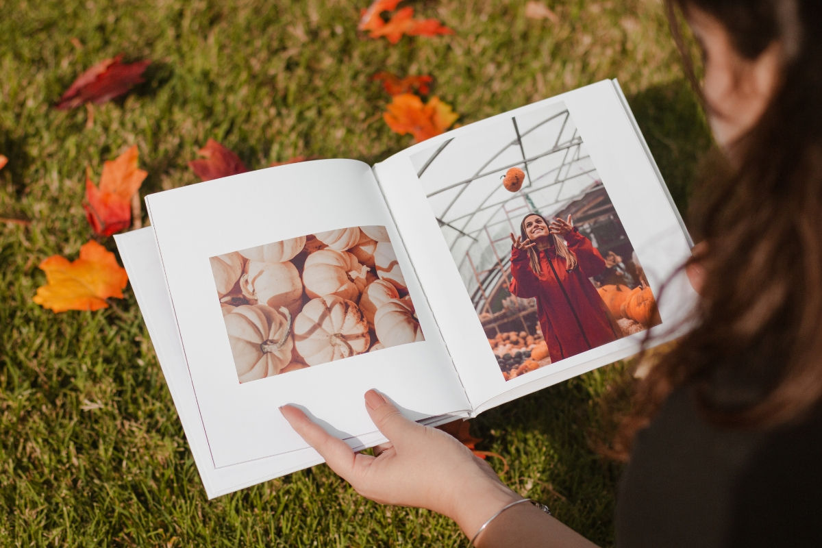 A woman looking at a photo book with pictures of pumpkins