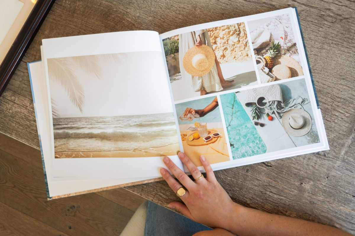 A hand resting on an open photo book of beach photos