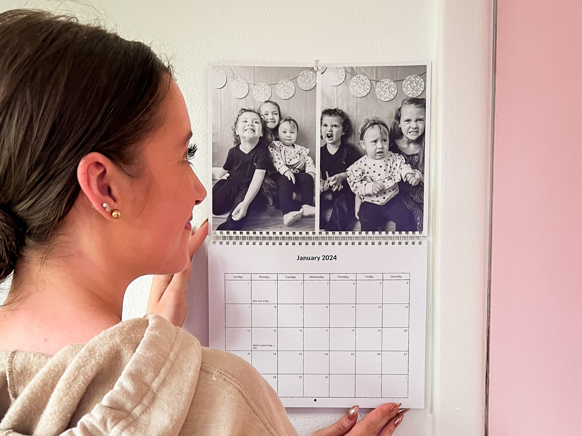 A woman staring a her wall calendar with pictures of her kids