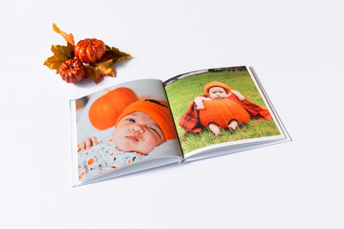 A photo book with pictures of a baby sitting in a hollow pumpkin