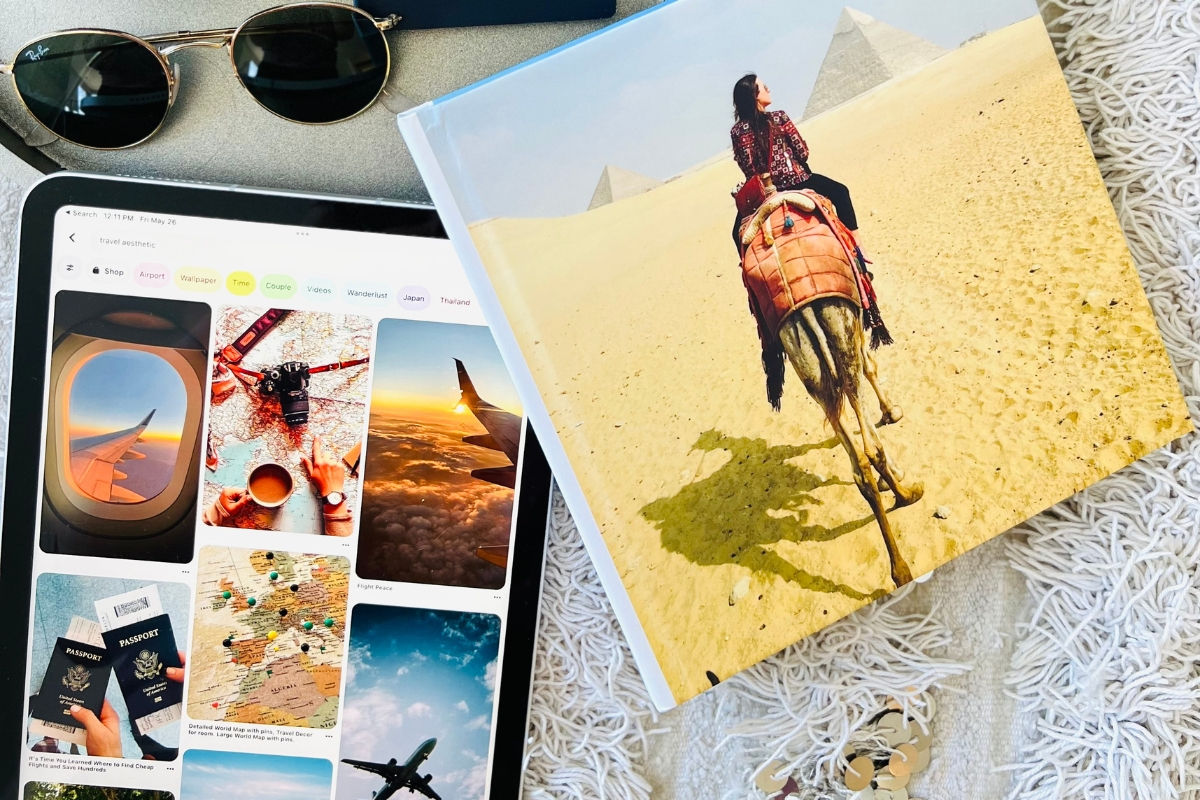 A tablet showing travel photos next to sunglasses and a book, with a woman on a camel near pyramids