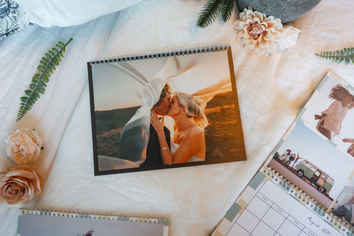 A wall calendar with a couple kissing on their wedding day and flowers around it.