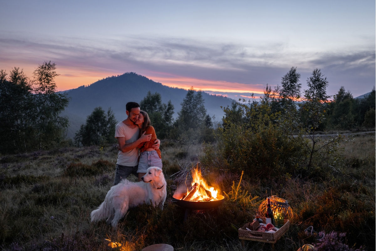 A couple and their dog spending time with a firepit