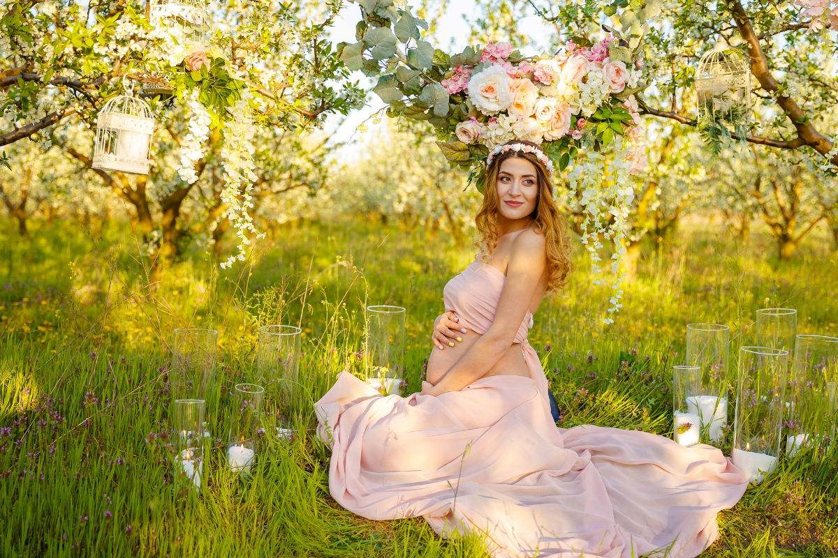 An etherial pregnant woman posing with a flowy dress and flower crown 