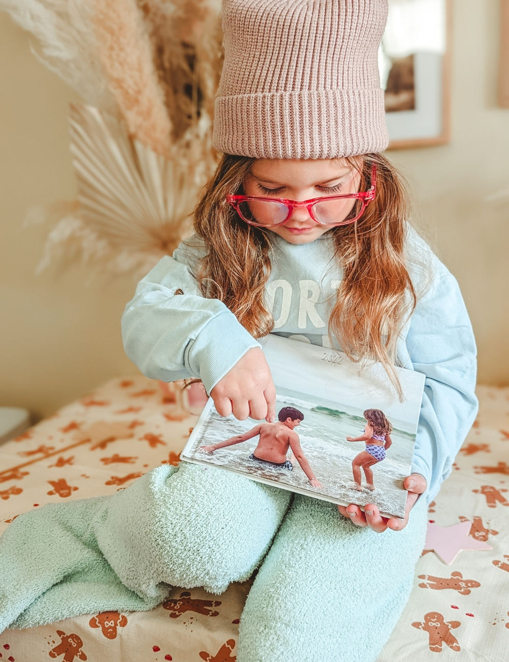 a young girl pointing at a photo book cover with her and her brother on it