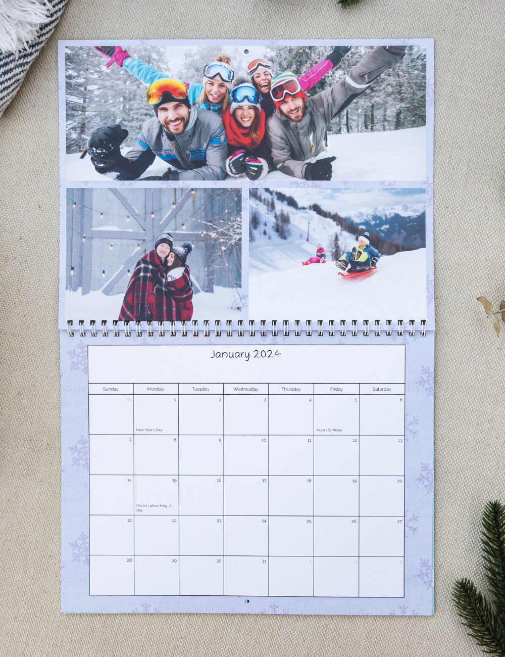 A wall calendar depicting fun ski memories with family and a snowflake designed background