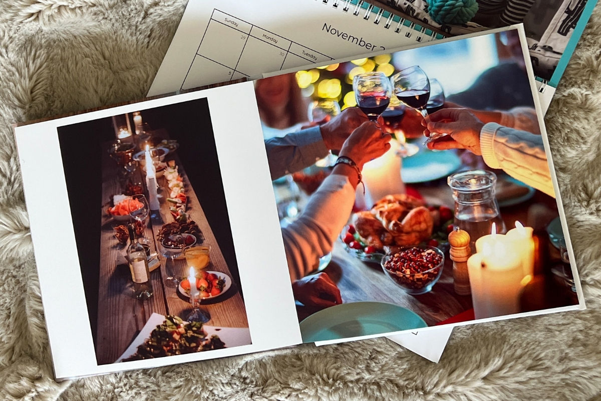SimplePrints photo book open on top of a SimplePrints. Pages have images of people cheering and sharing dinner.