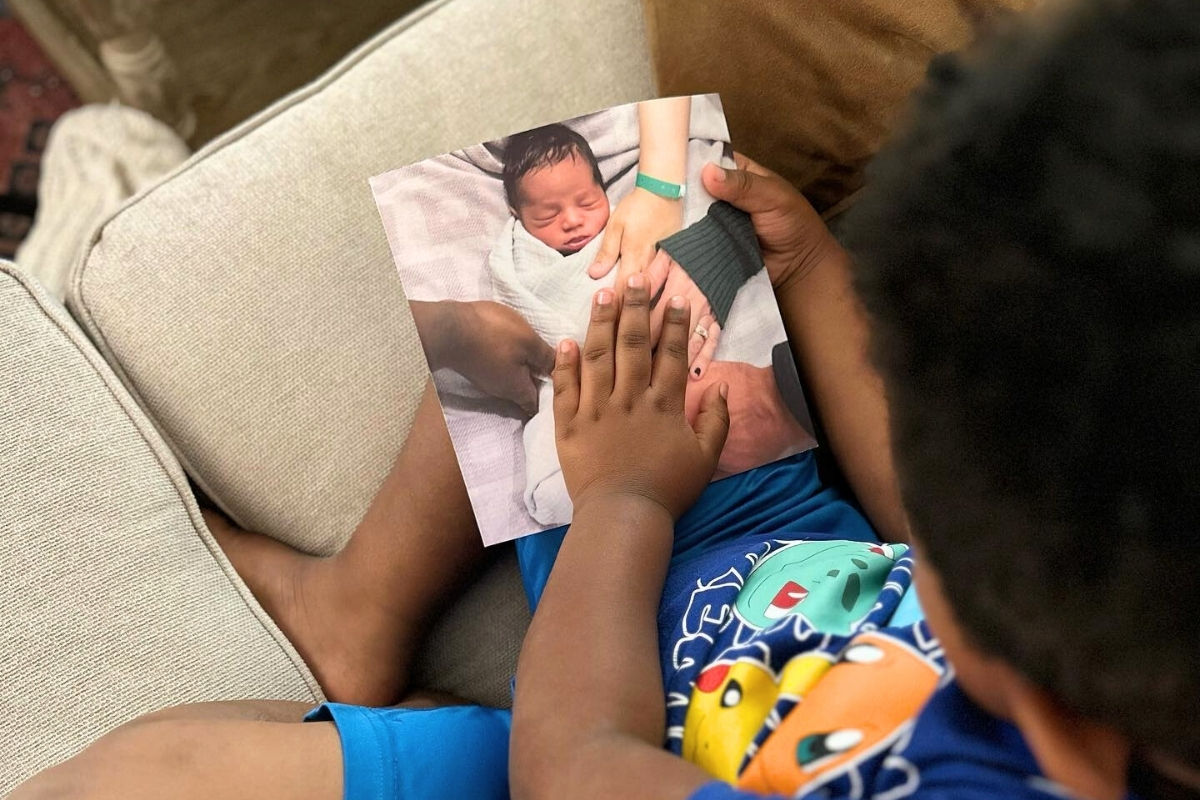 a boy holding his hand on the cover of a photo book with a cover of him as a baby
