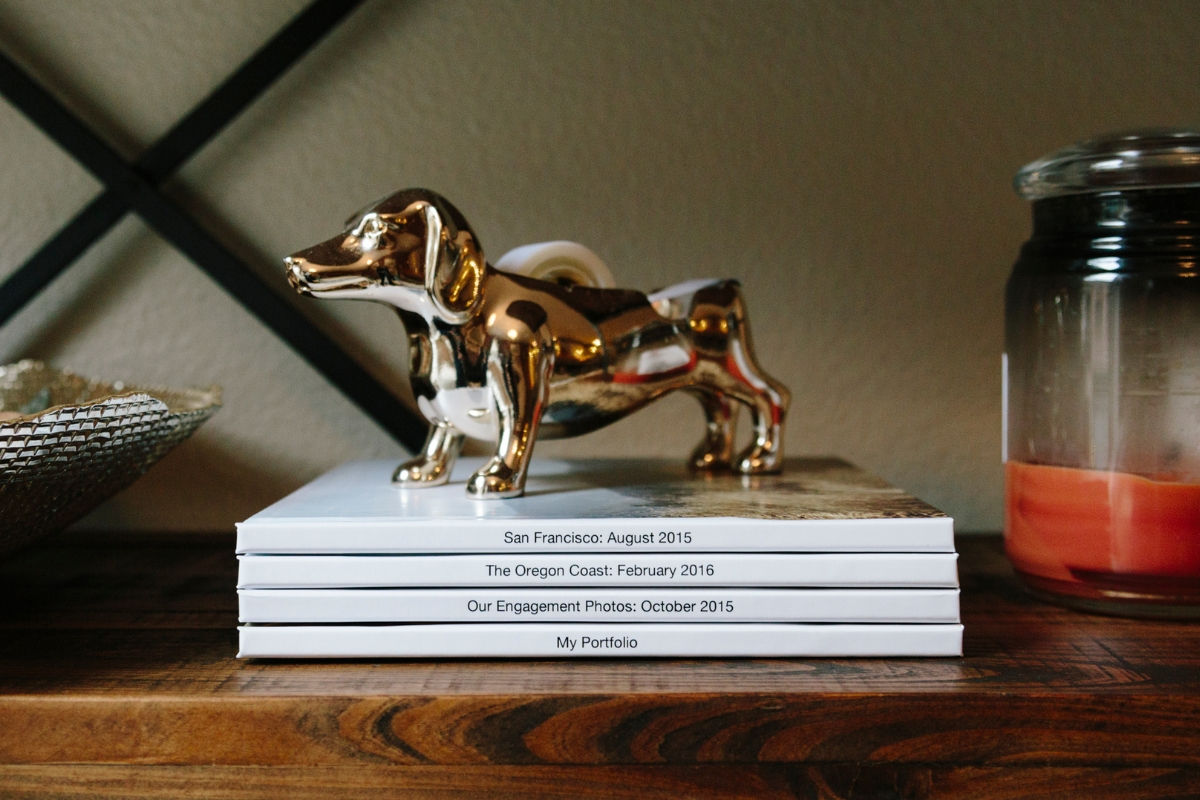A collection of photo books stacked on a shelf, each labeled with a different trip
