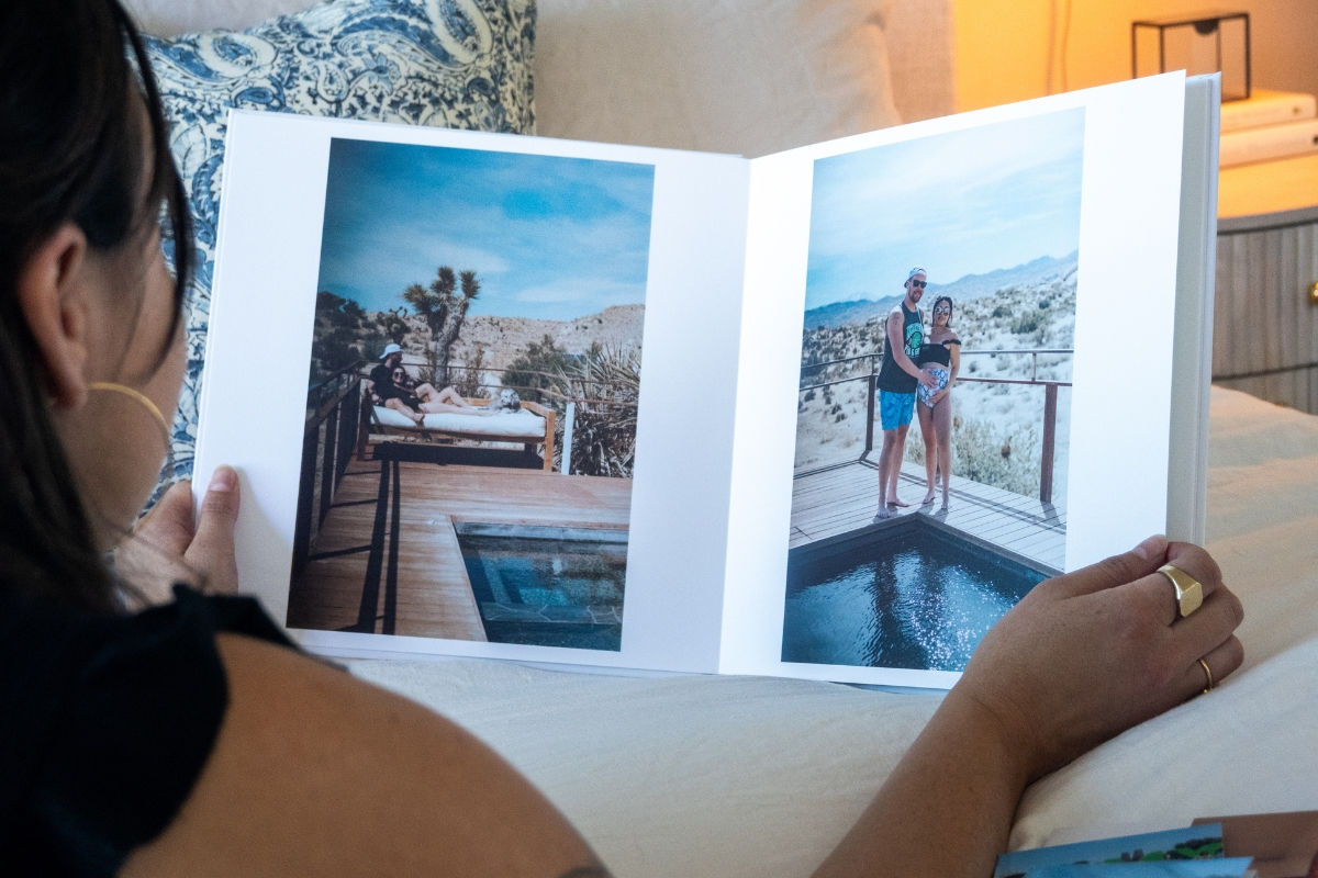 a woman flipping through a photo book with photos of a desert vacation