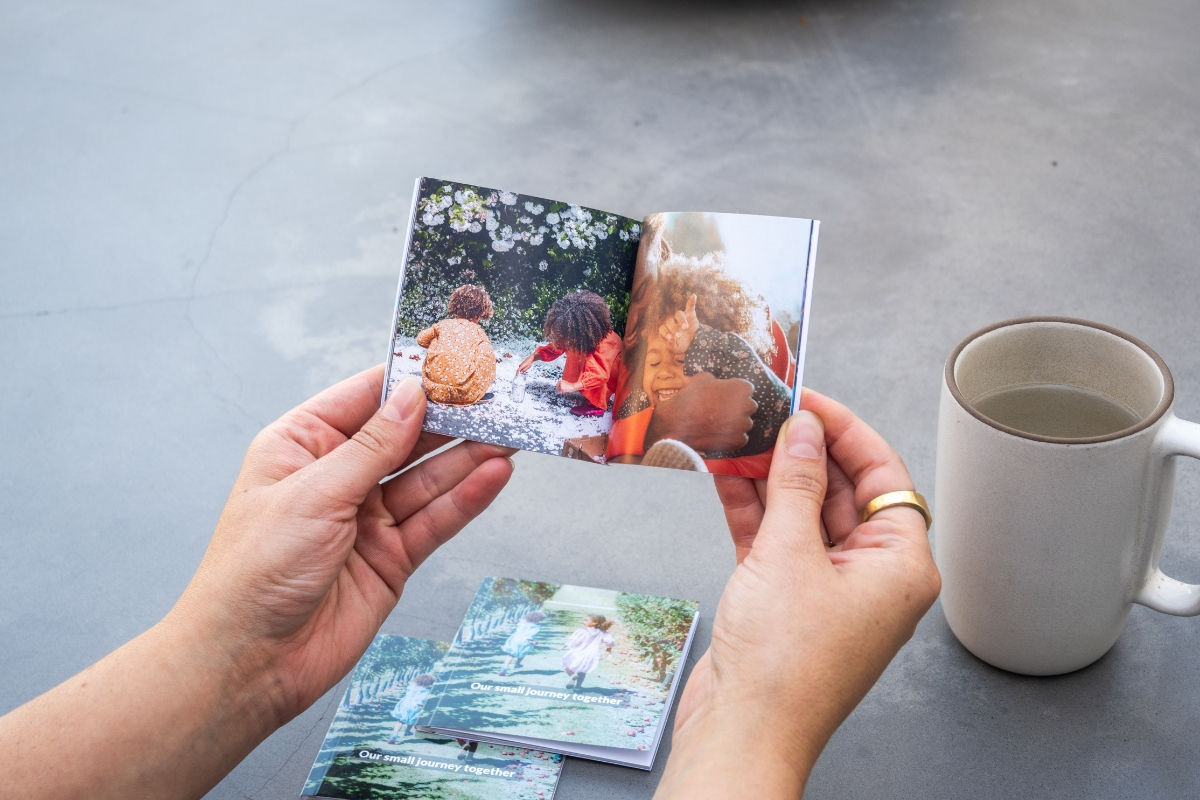 Hands holding a mini book personalized gift depicting children playing