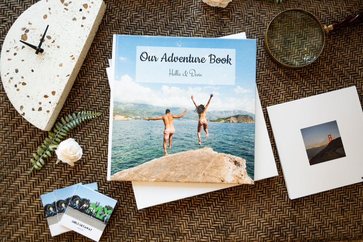 A photo book of a couple jumping into the ocean titled "Our Adventure Book"