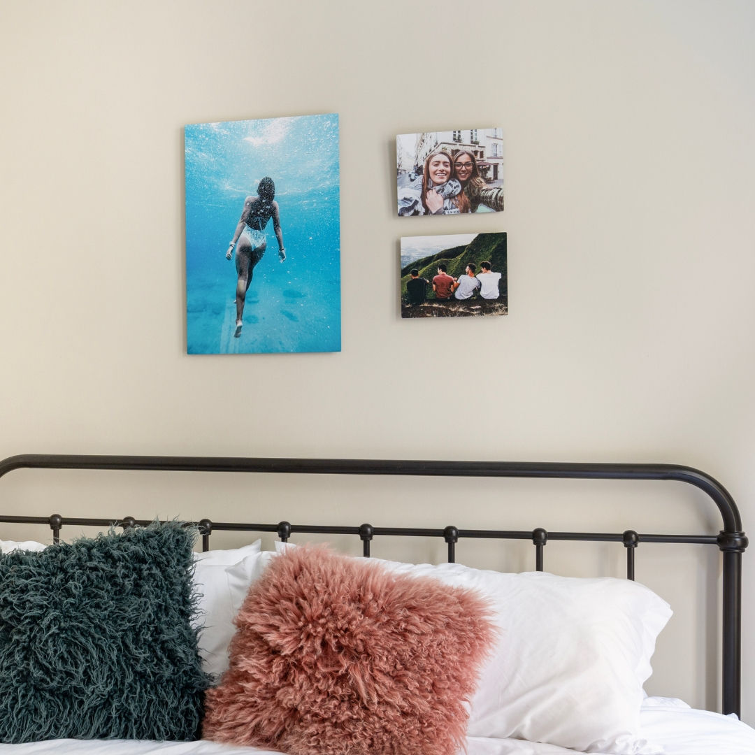 A bedroom with a collage wall of travel photos with friends