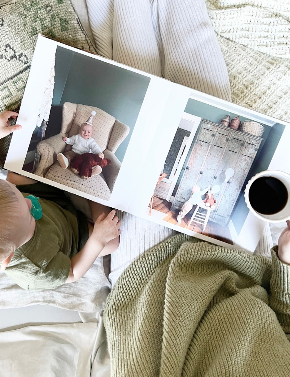 Woman holding coffee enjoying a photo book with her baby