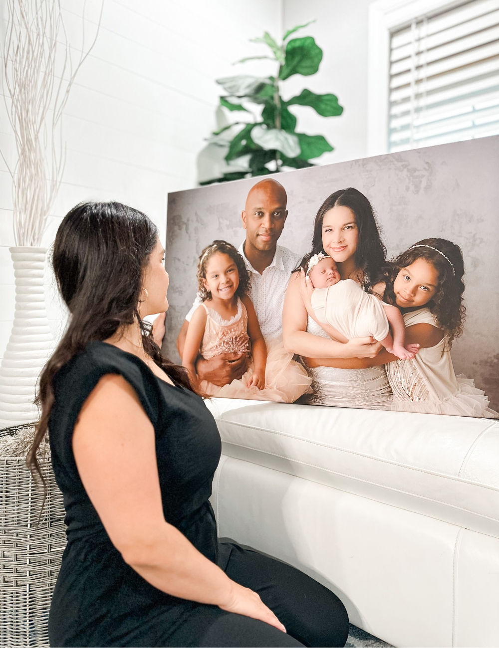 a women holding a canvas print of her and her family sitting on top of a mountain overlooking a lake