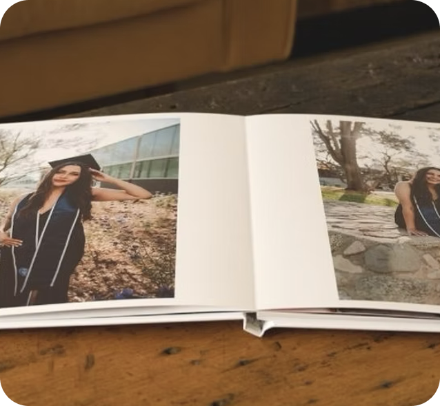 An open layflat photo book of graduation photos lying flat on a wooden table