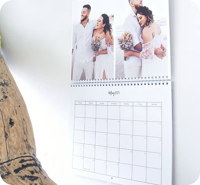 A wall calendar with three wedding photos above the month grid