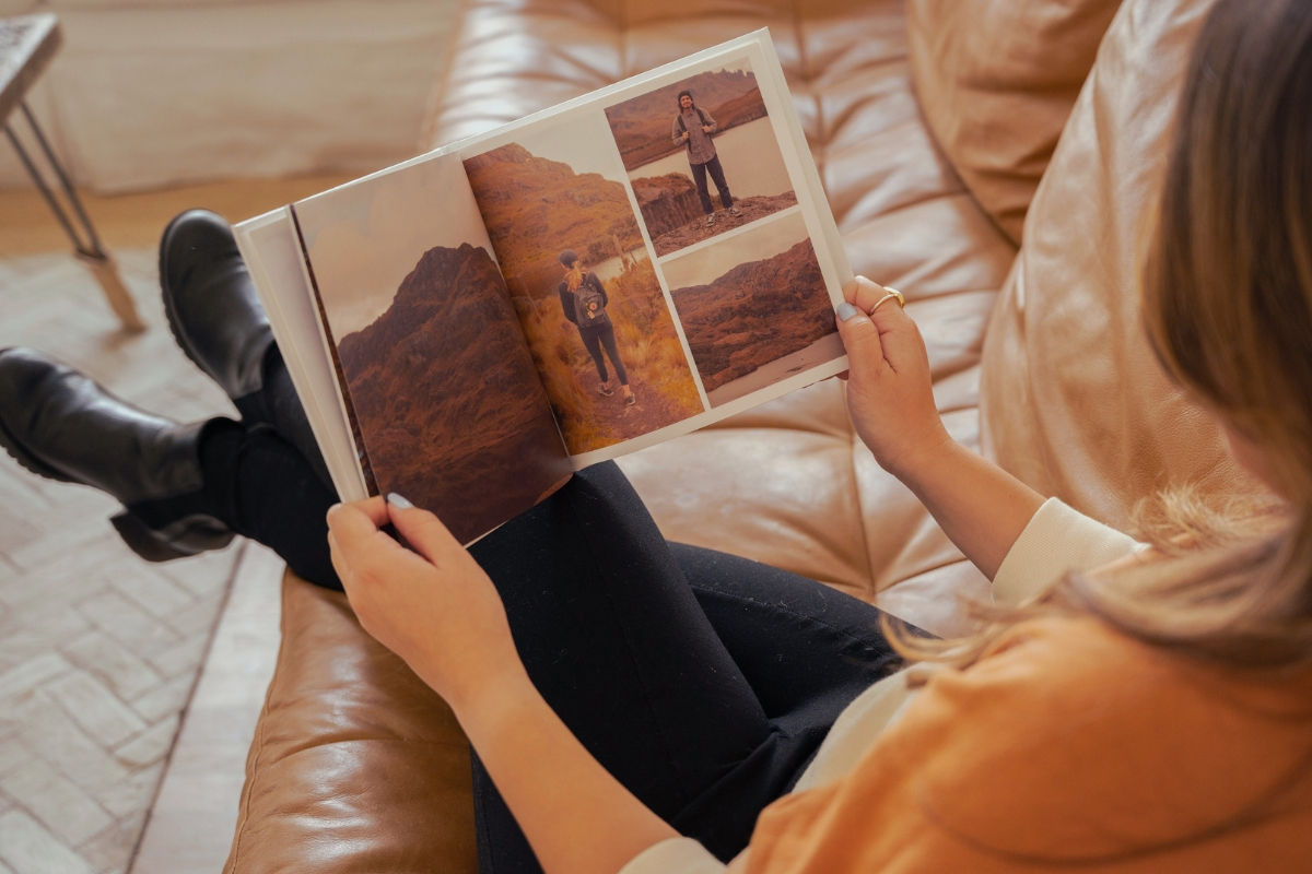 Woman sitting in a couch and looking at a SimplePrints Photo book