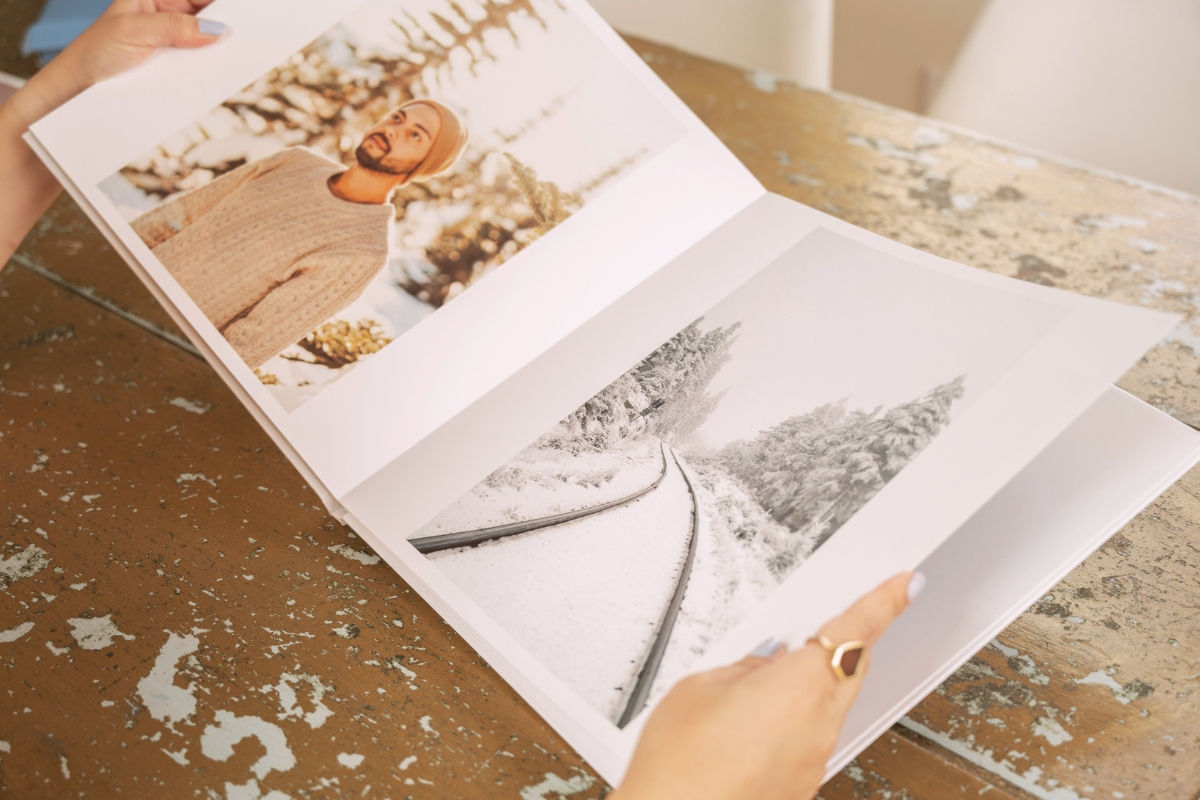 Person holding a SimplePrints hardcover photo book with images of winter