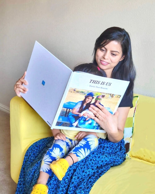Woman looking at her SimplePrints photo book with her baby